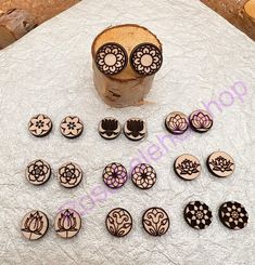 several wooden buttons with designs on them sitting on a white tablecloth next to some candles