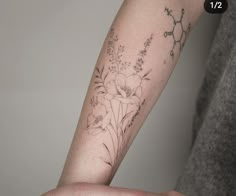 a woman's arm with flowers on it, and a ring around her wrist