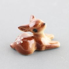 small ceramic deer figurine laying down on the ground