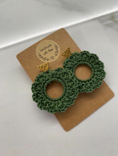 two green crochet earrings on top of a card