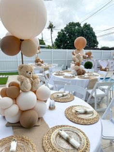 a teddy bear sitting on top of a table next to some plates and silverware