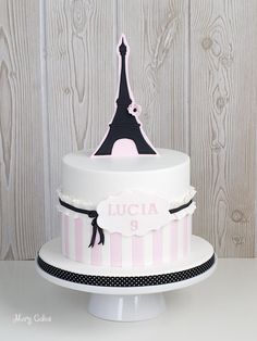 a three tiered cake with the eiffel tower on top is decorated in pink and black