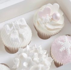 four cupcakes in a white box decorated with frosting and snowflakes