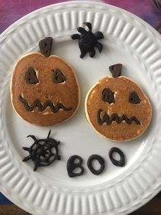 two pancakes decorated like jack o lanterns on a paper plate