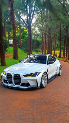 a white sports car parked in front of some trees on a brick road with red bricks