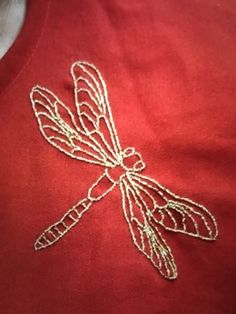 a red shirt with a dragonfly embroidered on it