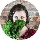 a woman holding up a bunch of broccoli in front of her face