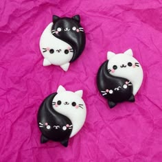 three small black and white cats on a pink background