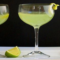 two glasses filled with green liquid and lime slices