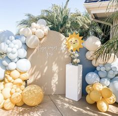 an outdoor area with balloons and decorations on the wall, palm trees in the background