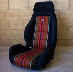 a car seat that is sitting in front of a brick wall and has stripes on it