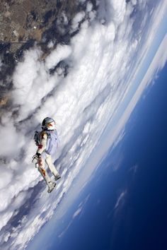 an astronaut is floating in the air above clouds and earth, looking down on him