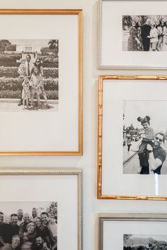 black and white photographs hang on the wall in front of two gold frames with people