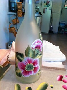 a glass bottle with flowers painted on it