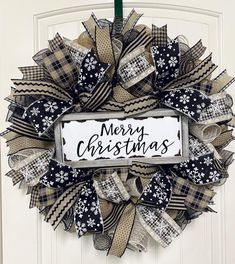 a christmas wreath hanging on a door with ribbon around it that says merry christmas written in black and white