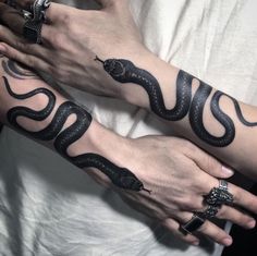 two people with tattoos on their arms holding onto one another's arm and the other hand