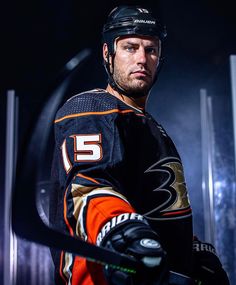 a professional hockey player is posing for a photo with his stick and helmet in hand