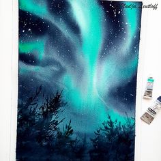 the painting is being worked on with watercolors and acrylic paint to make it look like an aurora bore