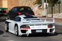 a white sports car driving down the street