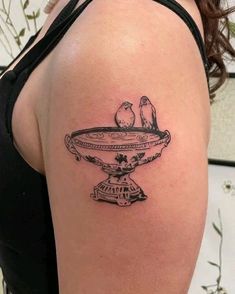 a woman's arm with two birds sitting on top of a cake dish tattoo