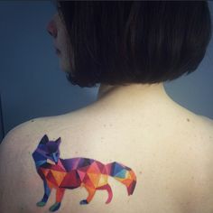 the back of a woman's shoulder with a colorful fox tattoo on it