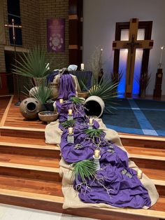 the altar is decorated with purple cloths and potted plants on top of wooden steps