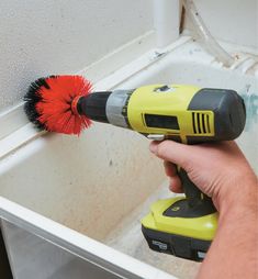 a person is using a brush to clean a sink with a power drill and sponge