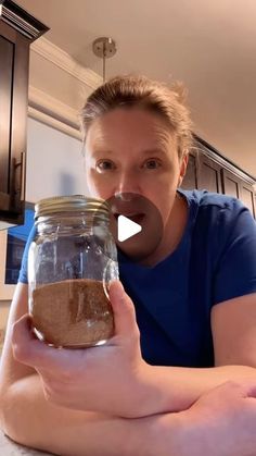 a woman holding a jar filled with brown stuff