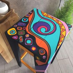 an artistically painted stool sits next to a plant