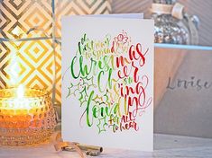 a greeting card with the words merry christmas written on it next to a lit candle