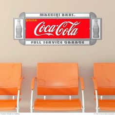 three orange chairs sitting in front of a coca cola sign