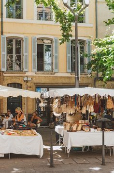 an outdoor market with people sitting at tables under umbrellas and lamps on the sidewalk