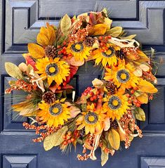 a wreath with sunflowers and berries is hanging on the front door's blue door