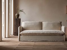 a white couch sitting next to a tall wooden table on top of a hard wood floor