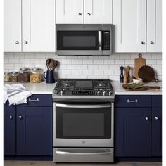 a stove top oven sitting inside of a kitchen next to blue cabinets and counter tops