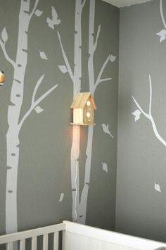 a baby's room with a birdhouse and tree decals on the wall