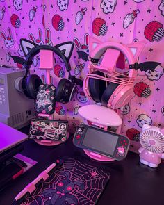 a desk topped with headphones and other items next to a wall covered in hello kitty wallpaper