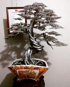 a bonsai tree sitting on top of a wooden table next to a framed picture