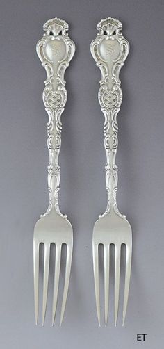 two forks with ornate designs on them are next to each other in front of a gray background