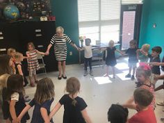 a group of children standing around each other in front of a woman with her arms out