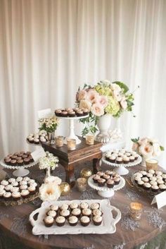 a table topped with lots of cupcakes next to a vase filled with flowers