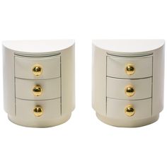 two white nightstands with gold knobs on each side and one has a drawer