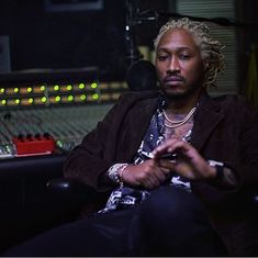 a man with dreadlocks sitting in front of a mixing desk and recording equipment