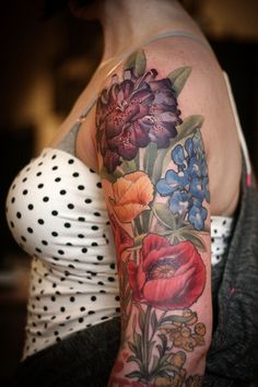 a woman's arm with flowers on it and polka dots around the top half