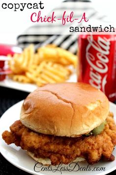 a chicken sandwich on a white plate next to some french fries and a can of coke