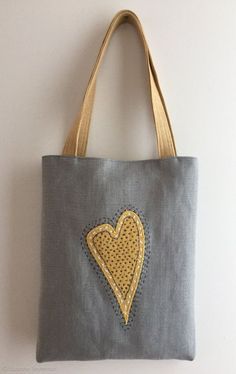 a gray bag with a yellow heart embroidered on the front and side, hanging from a wall