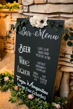 a chalkboard sign with flowers on it sitting in front of a stone wall that says beer menu