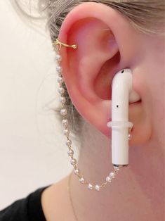 an ear piercing is attached to a white beaded ball chain with a tiny nose piece