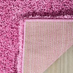 a pink rug on top of a wooden floor next to a piece of wood with an area rug underneath it