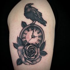 a black bird sitting on top of a clock with roses around it's sides